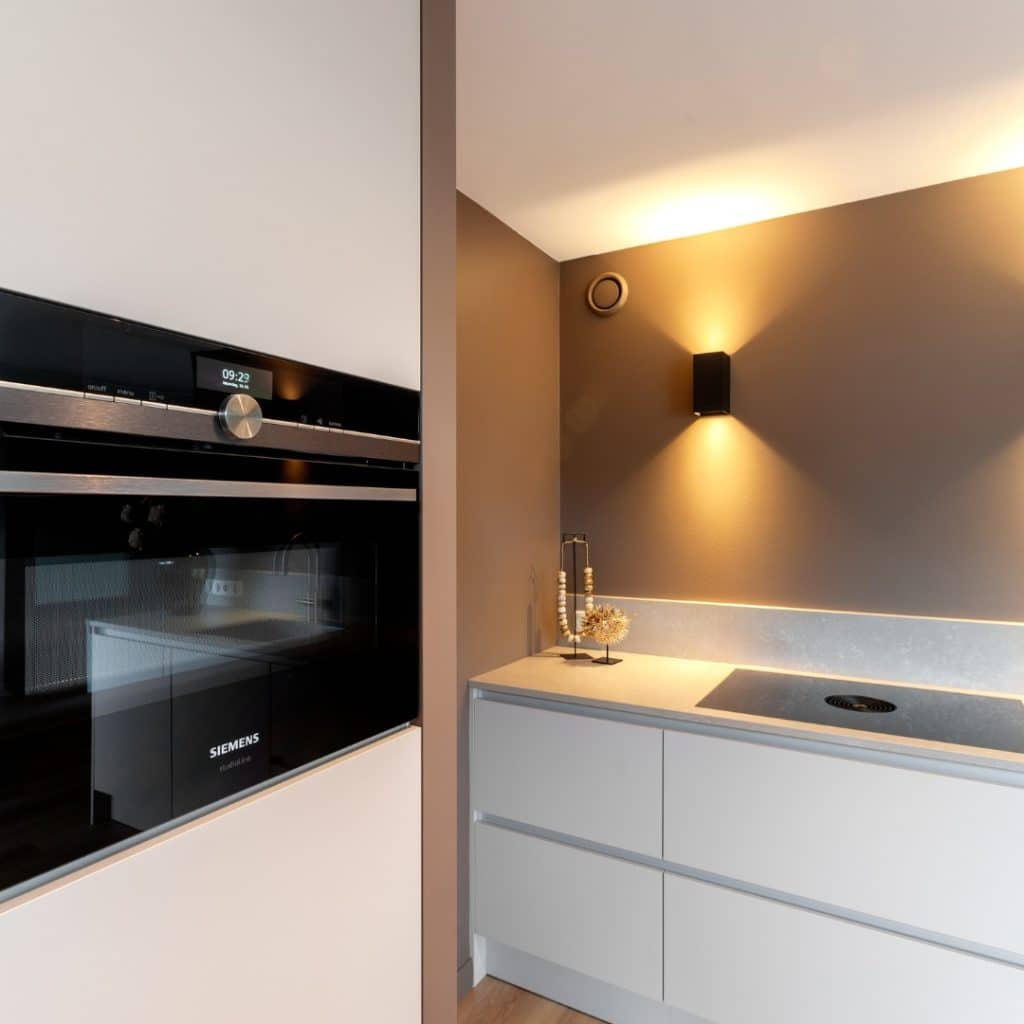Moderne keuken met een naadloos geïntegreerde Siemens keukenapparatuur in een witte kastwand