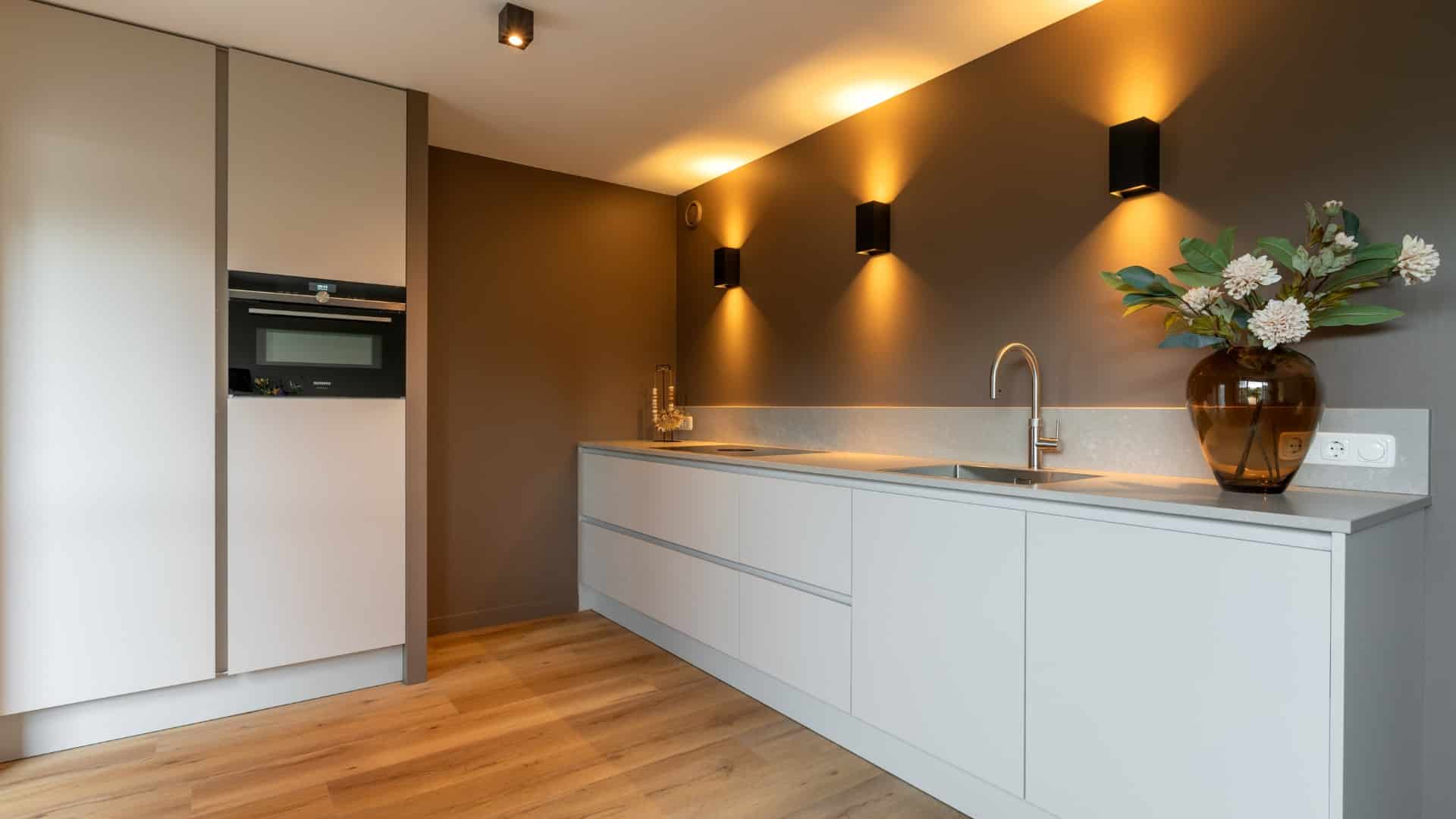 Moderne minimalistische witte keuken met mat witte kasten en een betonlook keukenblad