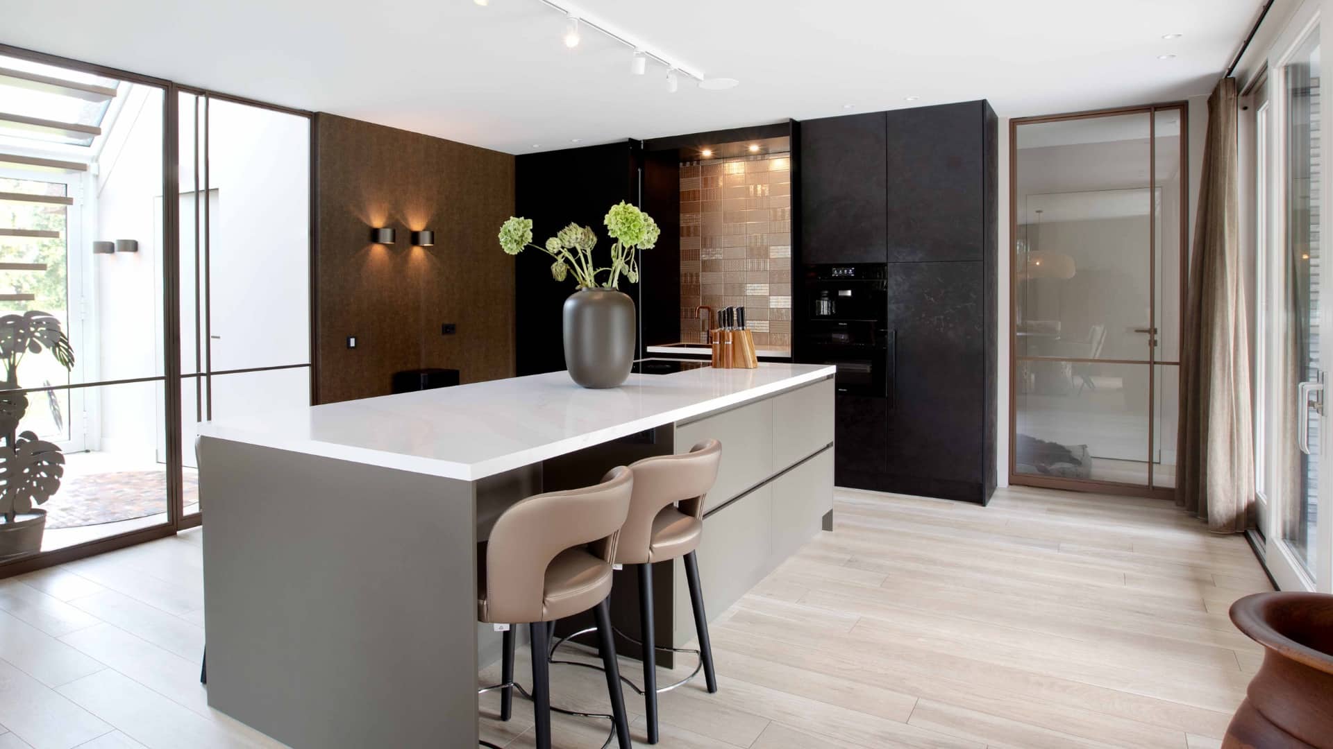 Taupe kookeiland met een licht marmerlook keukenblad composiet in luxe woonkeuken